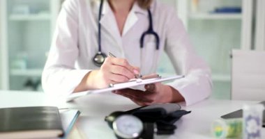 Doctor writing in medical documents on clipboard in clinic closeup 4k movie. Keeping patient medical history concept
