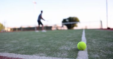 Tennis ball lying on court against background of players closeup 4k movie slow motion. Healthy lifestyle sport concept 