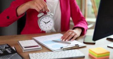 Businesswoman holding gray alarm clock in her hands in office closeup 4k movie slow motion. Time management concept 