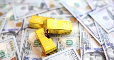 Gold bars lying on set of dollar bills closeup 4k movie slow motion. Gold reserves concept 
