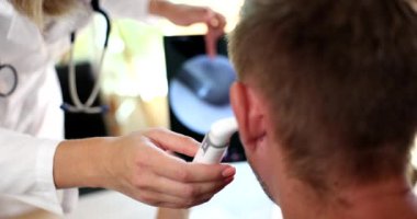 Doctor otorhinolaryngologist examining patient ear using modern digital otoscope closeup 4k movie slow motion. Diagnosis and treatment of otitis media concept 