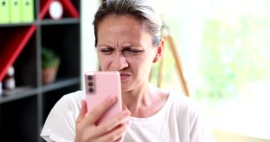 Sad woman with poor eyesight looking at mobile phone screen 4k movie slow motion. Negative news online concept 