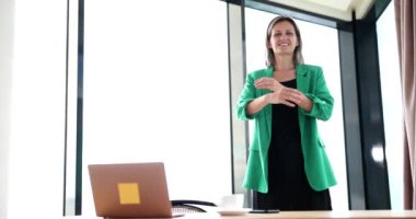 Smiling businesswoman in green suit crossing her arms in office 4k movie slow motion. Positive mood at work concept 