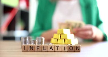 Word inflation on background of gold bars and coins 4k movie slow motion. Gold in inflation and deflation concept 