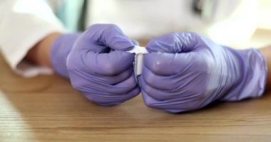 Doctor gynecologist in gloves opening antiinflammatory suppository closeup 4k movie slow motion. Hemorrhoid treatment concept 