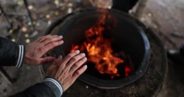 Homeless man warming his hands by fire on street closeup 4k movie slow motion. Life of people without fixed place of residence concept 