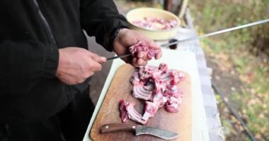 Male cook stringing pork ribs on skewer closeup 4k movie slow motion. Outdoor barbecue dinner concept 