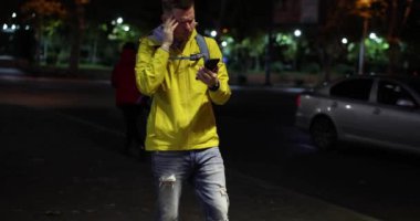 Tired male tourist got lost in city with mobile phone at night 4k movie slow motion. Problems with navigation in mobile phone apps concept