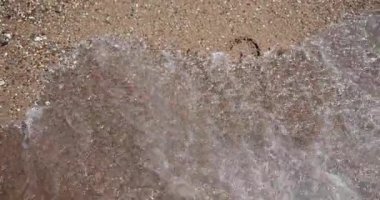 Incoming wave washes away inscription 2022 on sand. End of old and beginning of new year