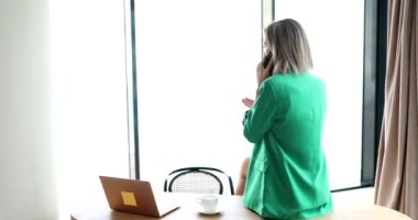 Businesswoman is sitting at desk in office talking on phone. Remote business negotiations with partner or client