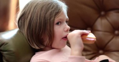 Little beautiful girl eats delicious sandwich at home. Snack food for children