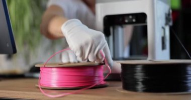 Engineer in gloves holds pink plastic for 3D printers. Production of plastic parts