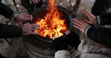 Illegal refugees or tourists warm hands in fire of barrel. Warming up in nature on cold nights