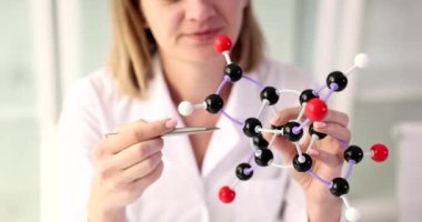 Kadın bilim adamı laboratuvarda moleküler yapının modeline bakıyor. Moleküler biyoloji yöntemleri