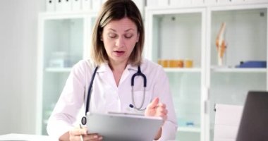 Stresli kadın doktor tablete bakar ve kötü haberleri okur. Klinikte çalışan hemşireler hata yapmaktan korkar.
