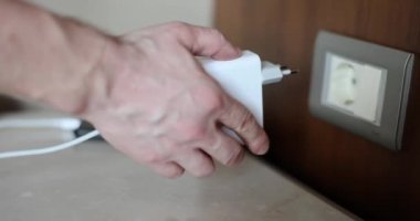 Cep telefonu şarj ediliyor. Adaptörü soket ve cep telefonu kavramına elle bağla