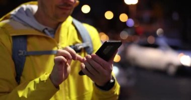 Akıllı telefon kullanan bir adam gece şehrinin caddesinde güzergah belirler. Taksi turistler için otel arama uygulaması