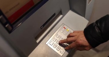ATM terminalinin şifresini elle çeviren bir adam. Para çekmek için güvenli parola girdisi