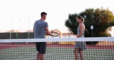 Couple of tennis players are walking on tennis court rear view. Training and communication at tennis practice