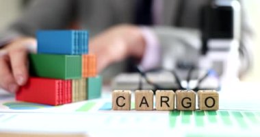 Business man moves stack of cargo containers on office table with financial documents. Container transportation and logistics services for the delivery of goods