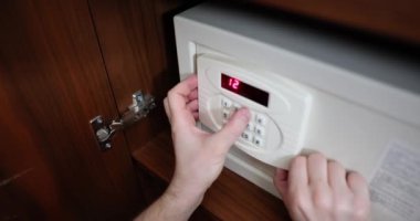 Man hand opens and closes safe hidden in closet in hotel. Security of funds of tourists and travelers
