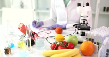 Scientist analyzes fruits and vegetables grown in laboratory using device. Microbiologist working with food in modern laboratory