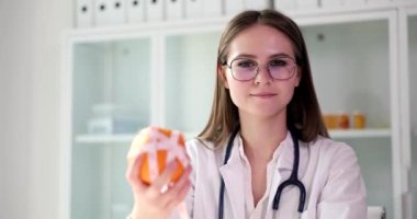 Nutritionist holds orange or tangerine fruit and measuring tape in hand. Doctor advice to eat healthy food with vitamins