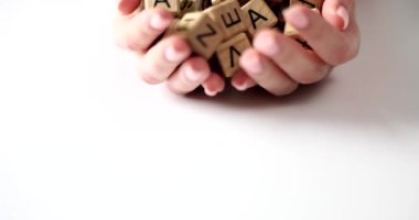 Hands of woman scatter lot of wooden cubes with letters of English alphabet. Dyslexic speech and reading disorders