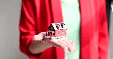 Woman agent or realtor is holding small house closeup in hands. Purchase rent property insurance