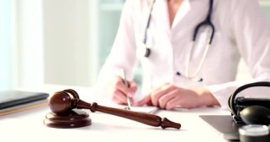 Tıp kliniğinin masasındaki tahta tokmak ve doktor evrakları dolduruyor. Doktorlar için hukuki destek