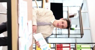 Young businessman marketer holds weekly remote online meetings about financial expenses virtual video. Sitting at table and showing sales chart report to camera