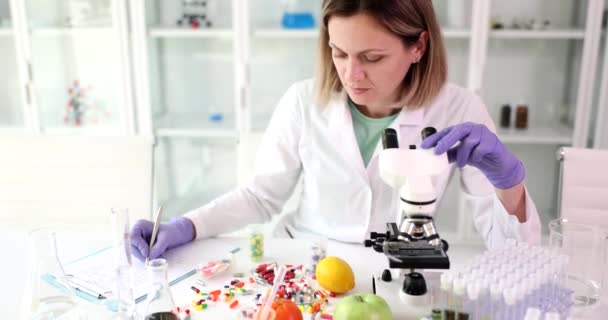 Female Scientist Works Microscope Analyzes Fruits Vegetables Writes Notes Reports — Vídeos de Stock