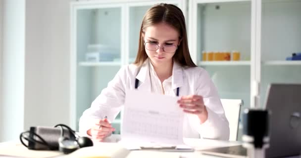 女性医師は 研修生の患者の健康診断や医学教育を検討します 患者健康診断医療計算と健康保険 — ストック動画