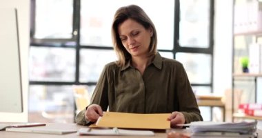 Business woman takes out documents from yellow envelope from bank. Receiving business correspondence