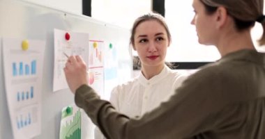 Woman manager explaining to trainee principles of working in business on charts on board 4k movie slow motion. Business development school concept