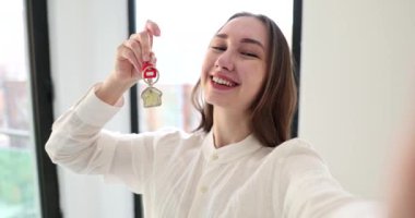 Satisfied woman taking selfie with apartment keys in hands 4k movie slow motion. Buying real estate concept