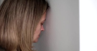 Sad woman with depression banging her head against wall 4k movie slow motion. Exit in stressful situations concept