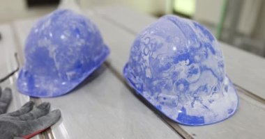 Dirty protective construction helmets lying on floor laminate closeup 4k movie slow motion. Construction work safety equipment concept