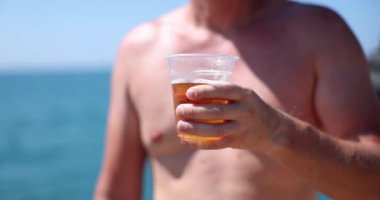 Young man drinking cold beer at beach bar enjoying summer vacation. Summer vacation relaxing and drinking alcohol