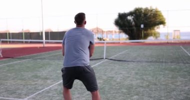 Amateur tennis player plays tennis on court. Man hitting ball on tennis court