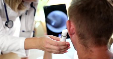 ENT doctor with digital otoscope performs examination of ears of man. Ear pain treatment and hearing test