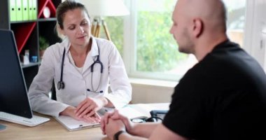 Kind female doctor holds hands of man with incurable disease. Therapist cardiologist oncologist supports talking about bad health test results