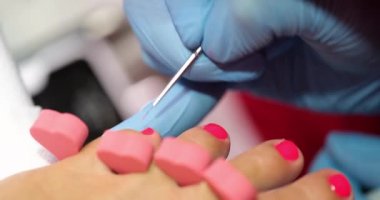 Manicurist draws on legs with brush. Beautiful red pedicure
