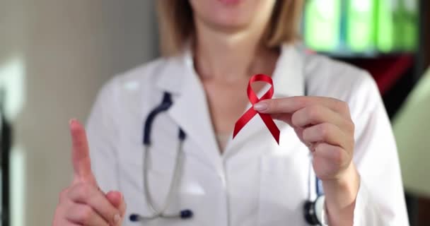 診療所の医師の手にHivエイズの赤いリボン 病気の慈善意識と支援のシンボル — ストック動画