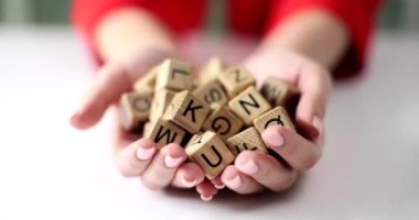 Woman hands hold cube with letters of English alphabet. Causes of reading difficulties in children with dyslexia