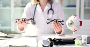 Ophthalmologist doctor shows two pairs of glasses for eye examination. Health care modern medicine and professional optician
