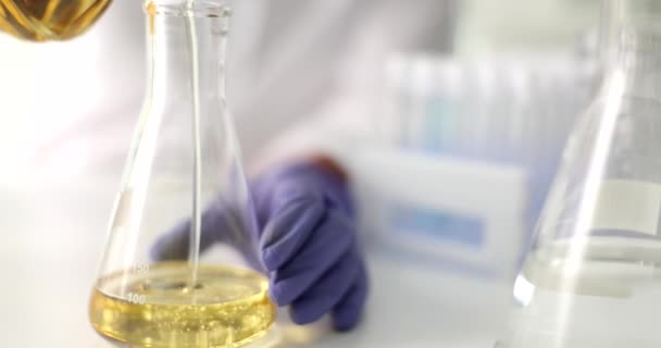 科学者の手は 実験室で試験管に高粘度油黄色潤滑油を注ぎます 自動車および産業用オイルの技術コンセプト — ストック動画