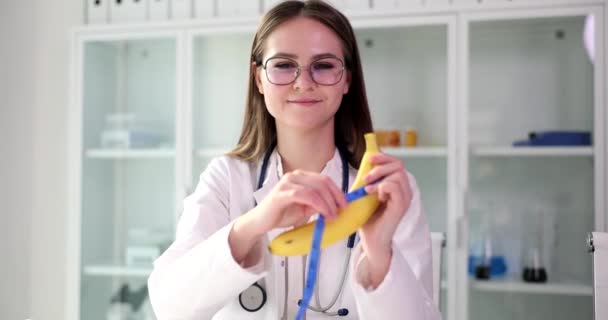 泌尿器科医はバナナを持ち 手でテープを測定しています 男性の性的障害 — ストック動画