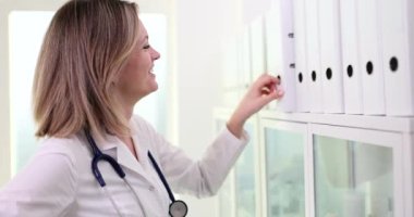 Doctor searches patient medical history in archive and takes folder from shelf. Medical documentation