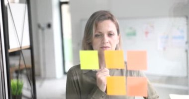 Business woman thinking new creative ideas working with paper note on glass wall. Share idea in office and business planning sticky note on glass